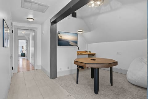 A cozy game room featuring a poker table, a kitchenette, and modern decor.