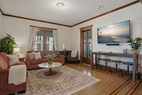 A warm and inviting living room with hardwood floors, comfortable sofas, and modern entertainment setup.