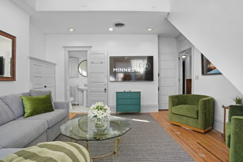 Living room with gray sofa, green chairs, and a mounted TV, showcasing a modern and cozy design.