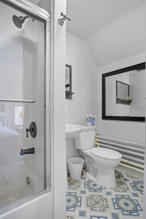 Compact bathroom with shower-tub combo, patterned floor tiles, and modern fixtures.