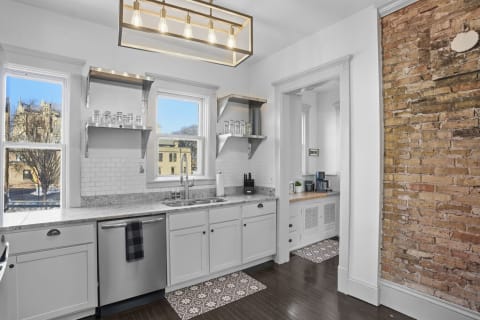 Interior view of a gourmet kitchen featuring granite countertops, stainless appliances, and an exposed brick wall.