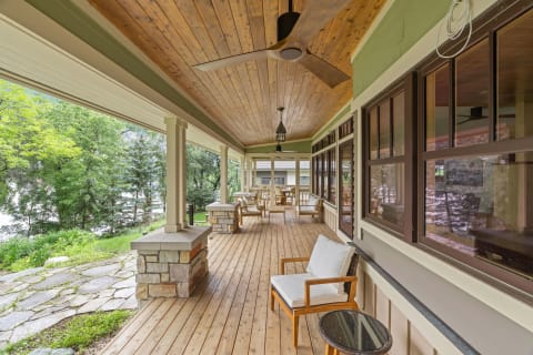A relaxing outdoor porch area with wooden flooring and stone pillars, featuring a chair and table.