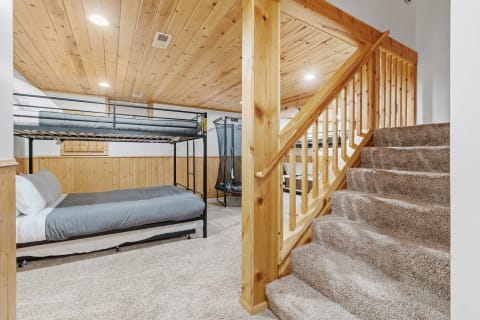 A comfortable basement room with a bunk bed and wooden staircase.