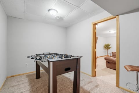 A cozy basement game room with a foosball table and brown leather sofas.