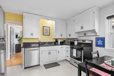 Modern kitchen with yellow walls, white cabinetry, and black countertops.