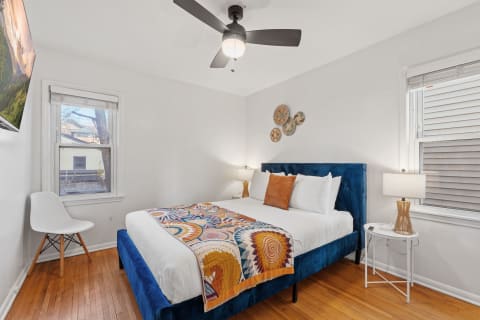 Cozy bedroom with a blue bed, colorful blanket, and artistic wall decor.