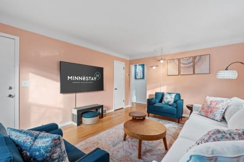 Cozy living room featuring blue sofas, wooden coffee table, and peach walls.