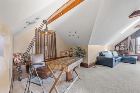 An attic room featuring a wooden desk, brown chair, blue sofa, and decorative elements.