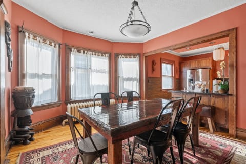 A warm dining area with a wooden table, black chairs, and terracotta walls.