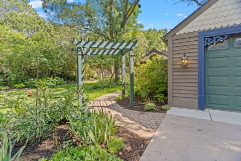Garden path with green trellis and vibrant plants.