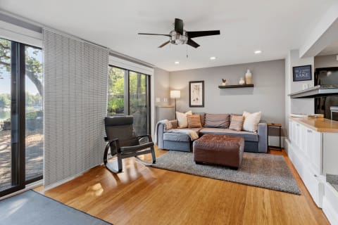 Interior view of a cozy living room with a lakeside view, featuring a sectional sofa and rocking chair.