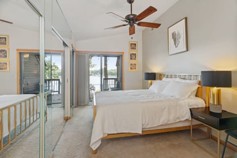 Modern bedroom with gold bed frame, black nightstands, lake view, and elegant decor.