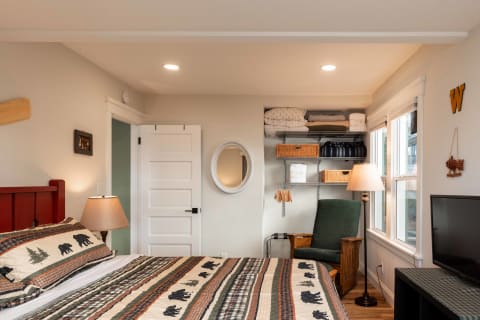 Cozy bedroom with a red headboard, bear-themed quilt, and rustic decor.