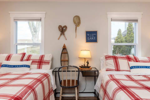 A cozy bedroom featuring twin beds, plaid bedding, and lake-themed decor.