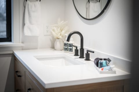 Modern bathroom sink area with white countertop, black faucet, and decorative elements.