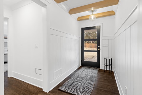 Bright entryway with black door and wood ceiling beams