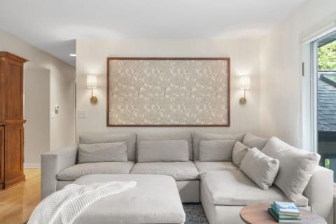 A cozy living room with a light gray sectional sofa and decorative wall art.