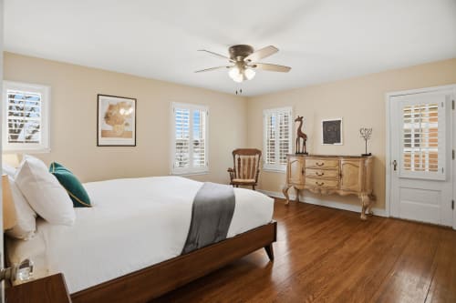 Unwind in your serene bedroom with gleaming hardwood floors, charming vintage furnishings, and peaceful natural light streaming through plantation shutters.