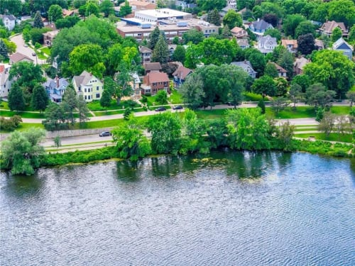 Aerial view of a charming lakefront neighborhood with tree-lined streets and diverse residential architecture.