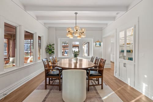 You'll love gathering around this elegant dining table with friends, bathed in warm light from the stunning modern chandelier overhead.