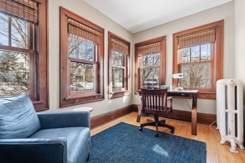 Settle into your bright workspace with rich wood details, cozy seating, and peaceful neighborhood views through elegant windows.