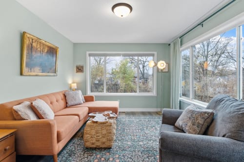 Unwind in your bright living room with cozy seating and peaceful views through large windows.