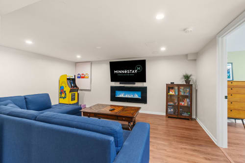Unwind in your spacious entertainment room with arcade games, cozy blue seating, and a warm fireplace for perfect game nights.
