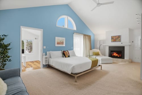 Unwind in your spacious master suite featuring a cozy fireplace, vaulted ceilings, and serene blue accent wall that creates the perfect retreat.