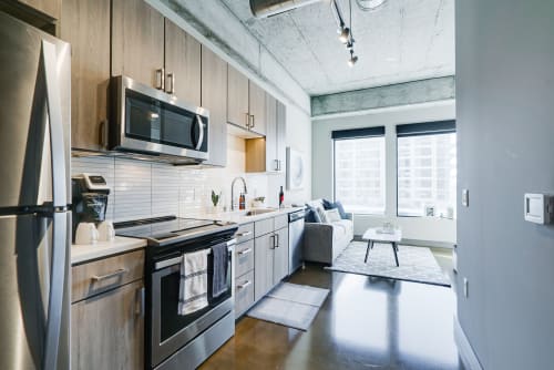 Your open-concept space features sleek kitchen with stainless appliances flowing into a cozy living area with exposed concrete beams overhead.