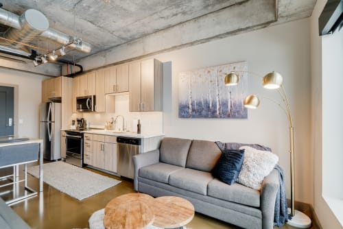 Unwind in your stylish loft with exposed concrete ceilings, modern kitchen, and cozy living area perfect for relaxing after exploring the city.
