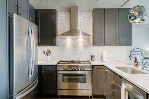 Your modern kitchen awaits with sleek gray cabinets, stainless steel appliances, and marble countertops perfect for preparing meals.