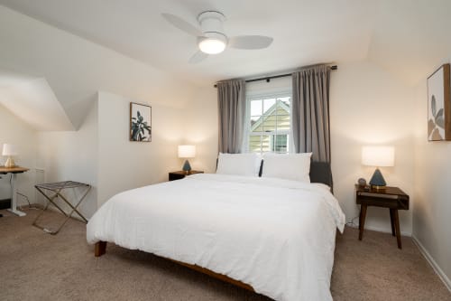 Sink into crisp white linens beneath your ceiling fan's gentle breeze, while warm bedside lighting creates the perfect atmosphere for relaxation.