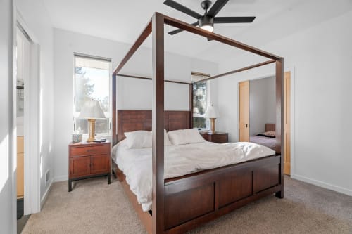 Drift off in your elegant four-poster bed beneath a gentle ceiling fan, with natural light streaming through windows.