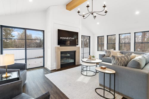 Unwind in your elegant living room with plush seating, warm fireplace, and large windows overlooking peaceful winter scenery.